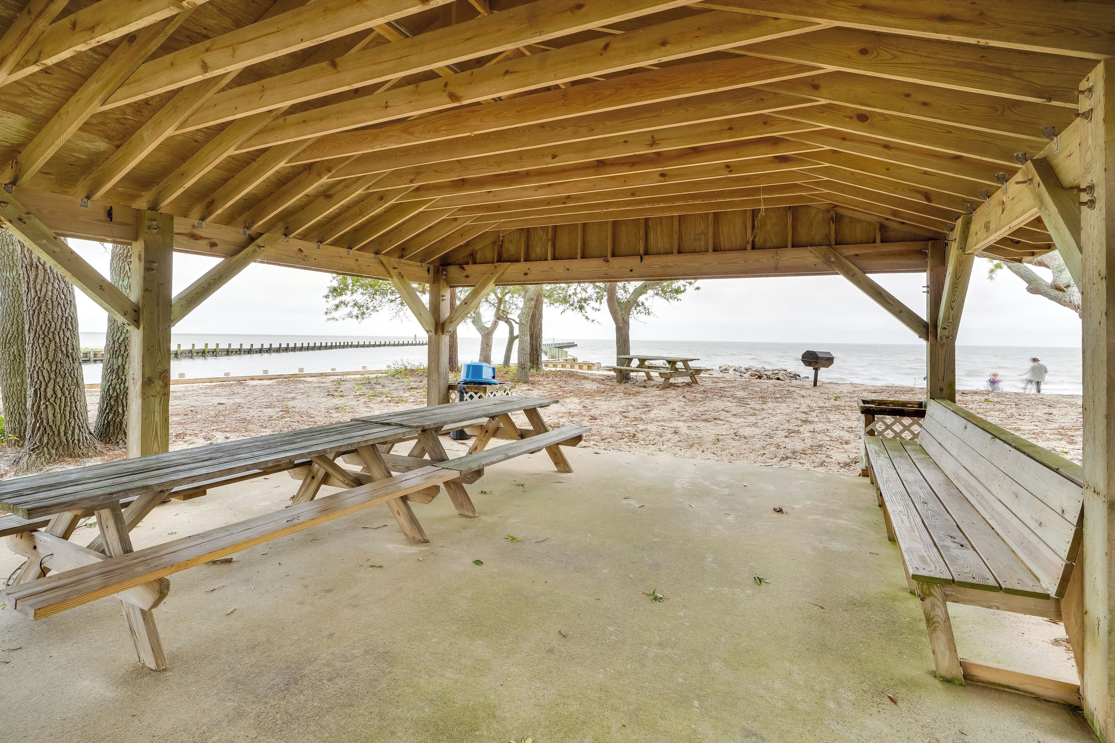 Een houten strandpaviljoen met picknicktafels en banken, met uitzicht op zee.