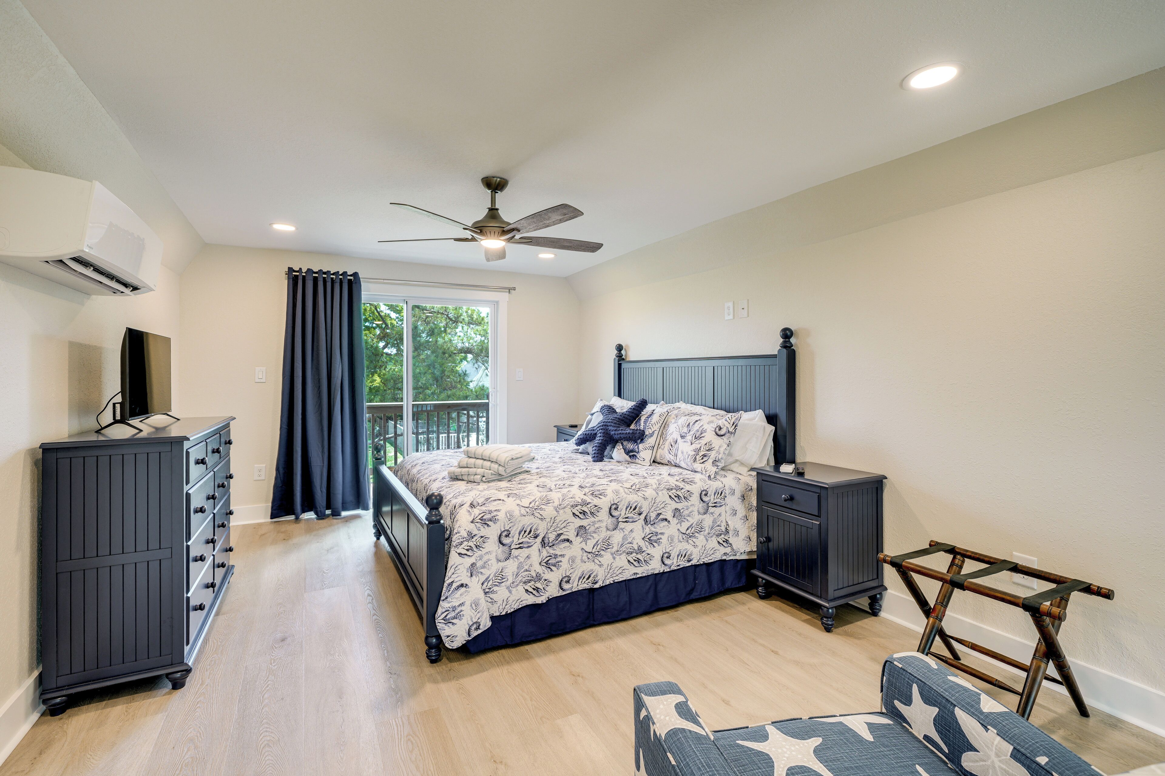 A bedroom with a bed, dresser, nightstand, and a ceiling fan.