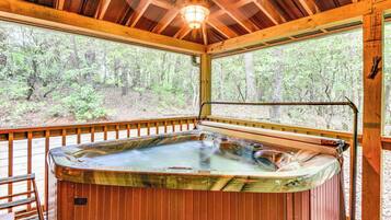 Un bain à remous dans un chalet en bois avec vue sur une forêt.