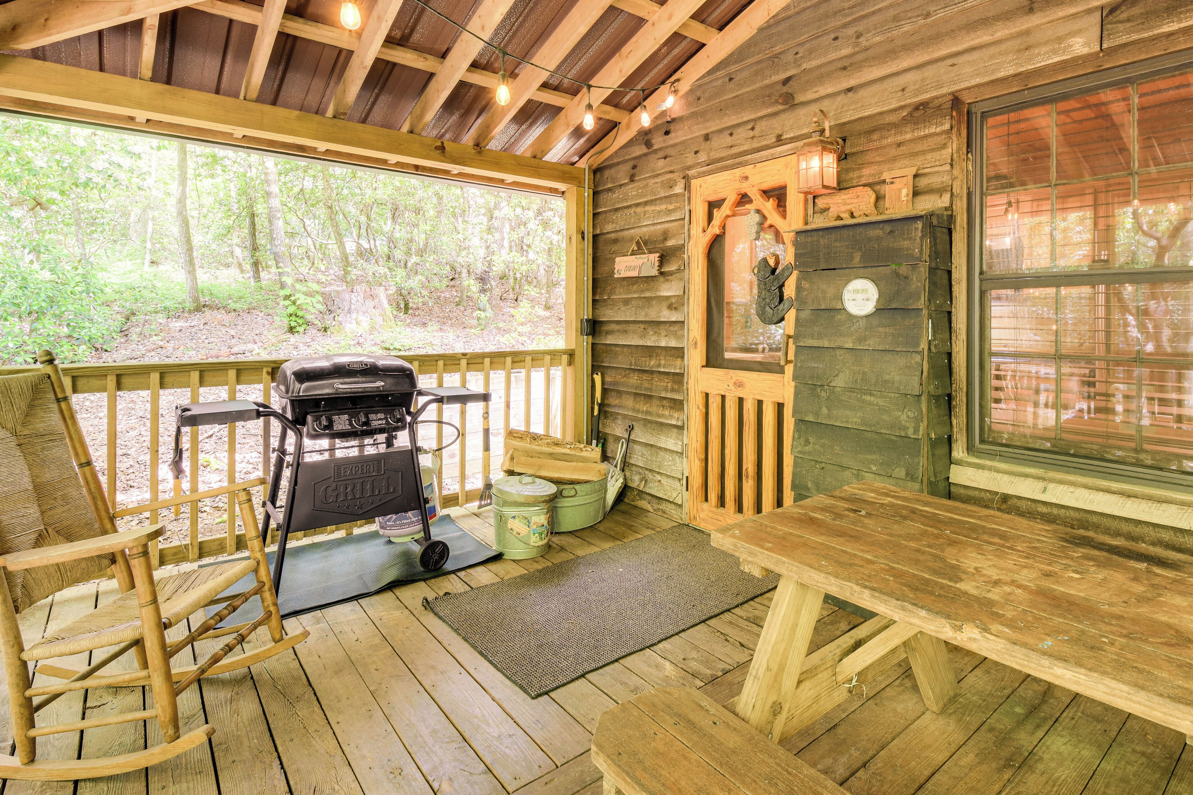 Eine Holzhütte mit Veranda, Grill, Schaukelstuhl und Tisch.