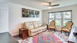 A living room with a beige leather sofa, two armchairs, a coffee table, and a patterned rug.