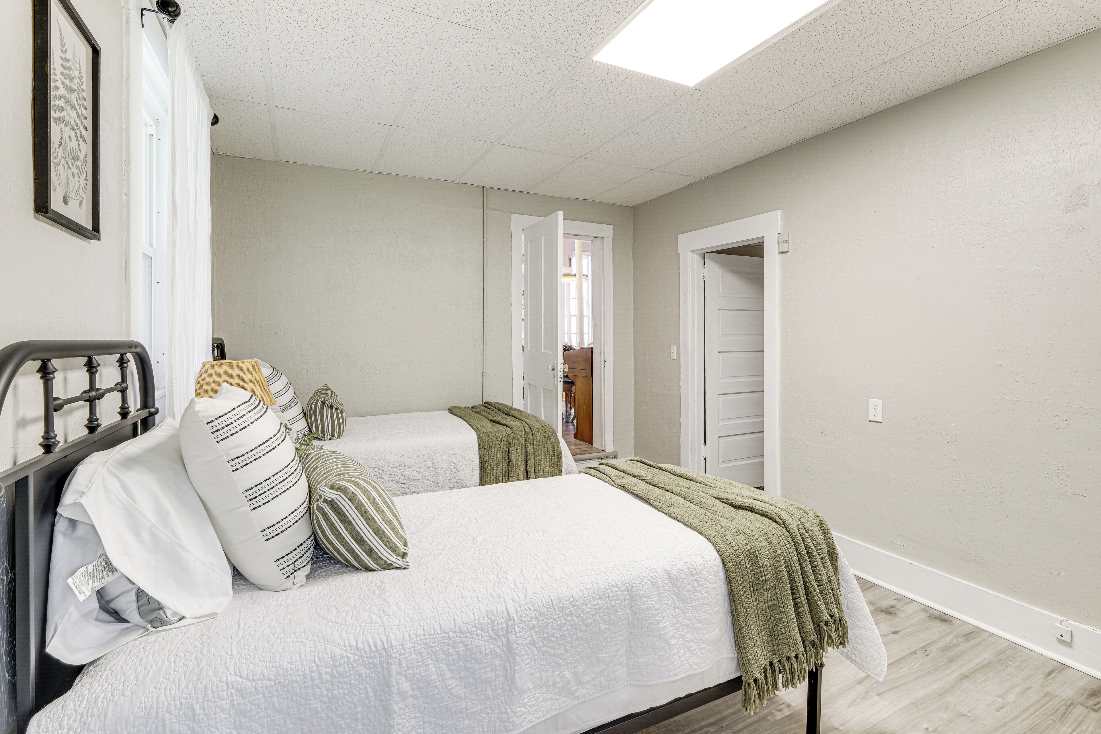 A bedroom with two beds, a wardrobe, and a door leading to another room.