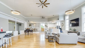 A spacious living room with hardwood floors, a large sofa, a coffee table, and a dining area with a piano. - Unique Church Turned Family Retreat: Relax & Enjoy (Alliance)