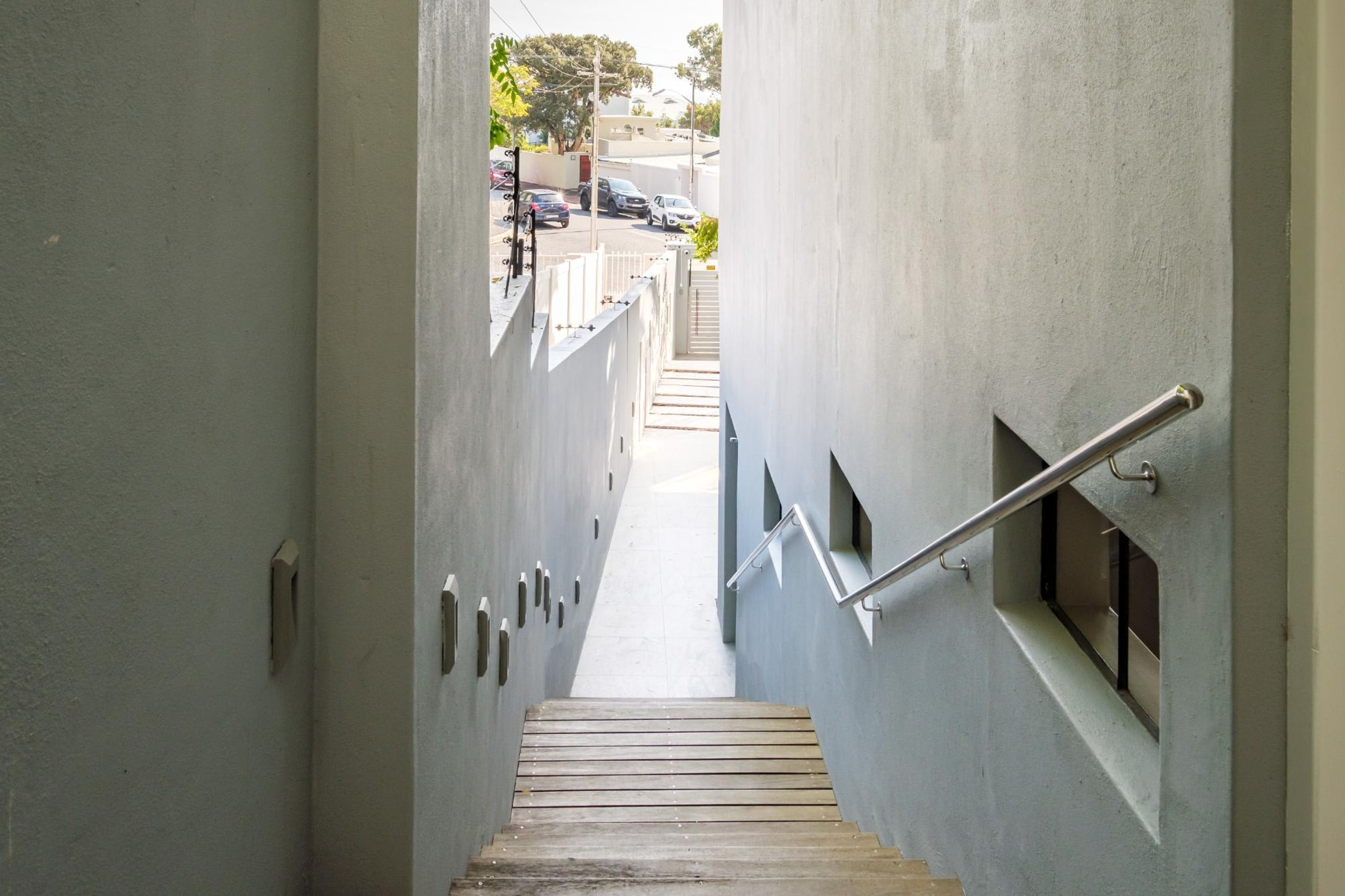 A narrow, concrete stairway leading to a landing with a metal handrail.