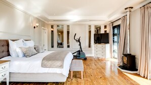 A spacious bedroom with a large bed, exercise equipment, a TV, and a fireplace. - 2bed Apt 5min Walk From Camps Bay Central Escape (Cape Town)