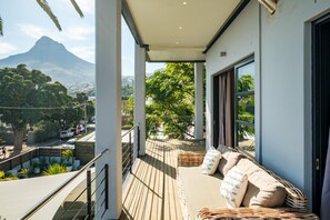 Ein Balkon mit einer Korbsitzgruppe, Blick auf einen Berg und eine Straße darunter.