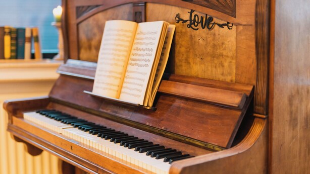 Un piano en bois sur lequel est posée une partition.
