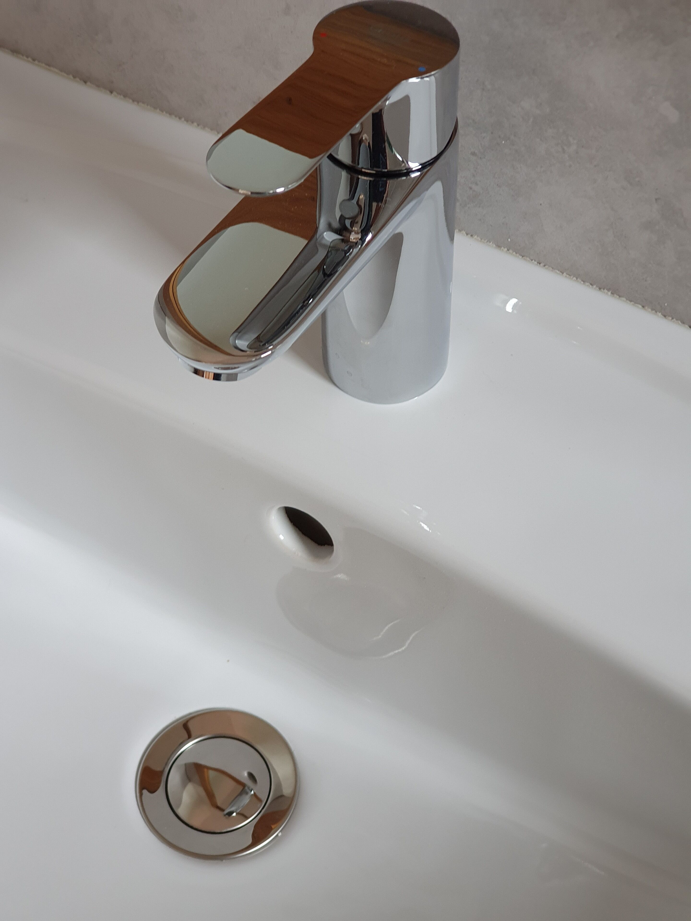 A chrome faucet with a wooden handle on a white sink.