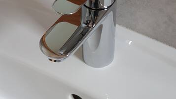 A chrome faucet with a wooden handle on a white sink.