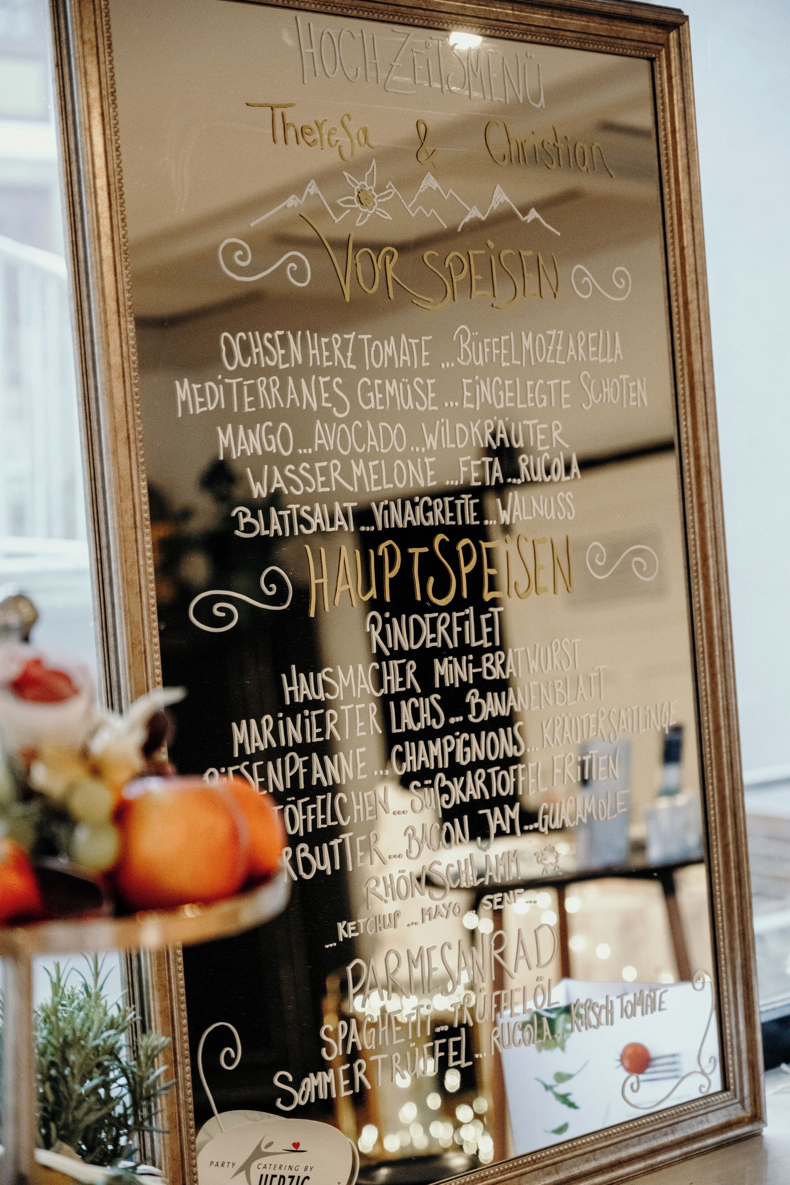 A framed menu listing various dishes and beverages, including items like 'Ochsenschwein Herztomate' and 'Mango...Avocado...Wildkraut'.