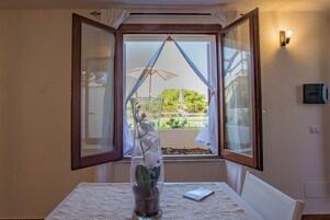 Una habitación con una mesa, un jarrón con flores y una ventana con cortinas.