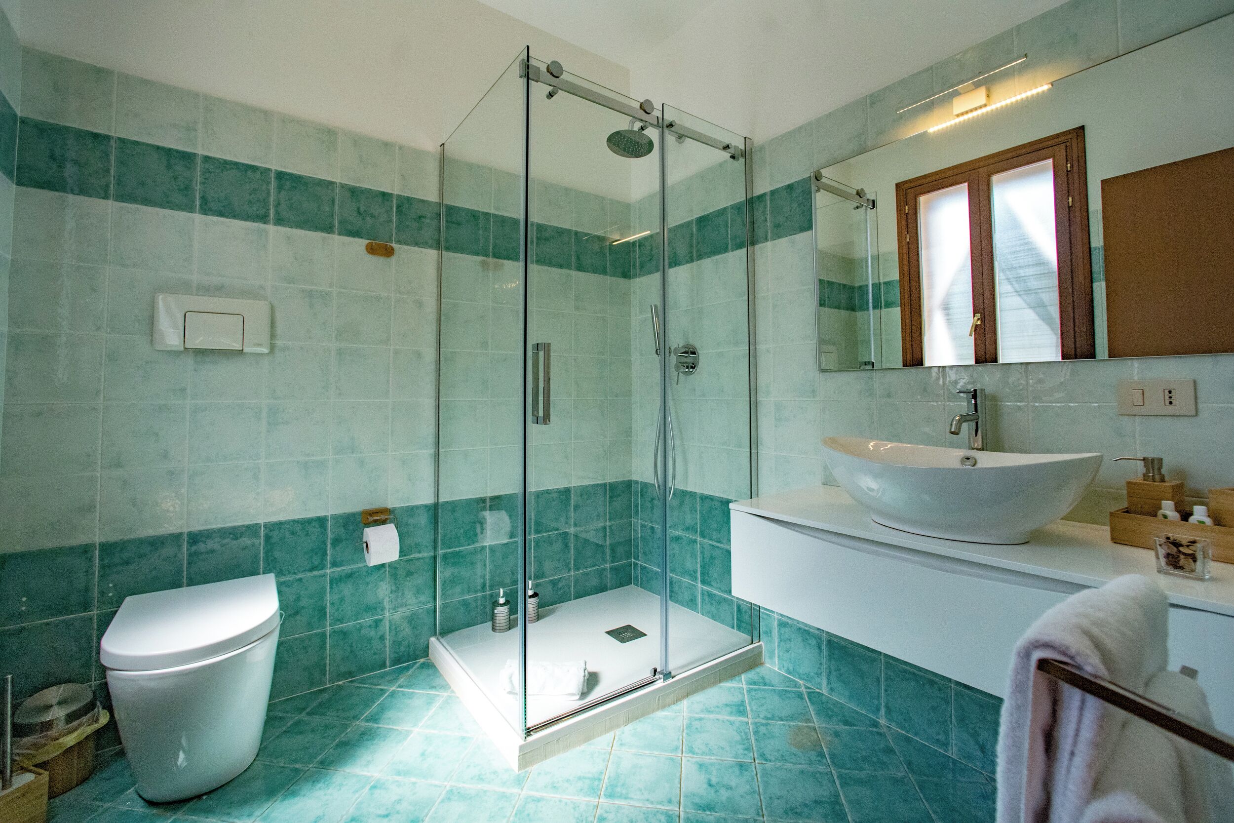 A bathroom with a glass-enclosed shower, a white sink, and a toilet.