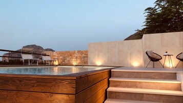Zona de piscina con escalones que conducen a un espacio de descanso con sillas y una mesa.