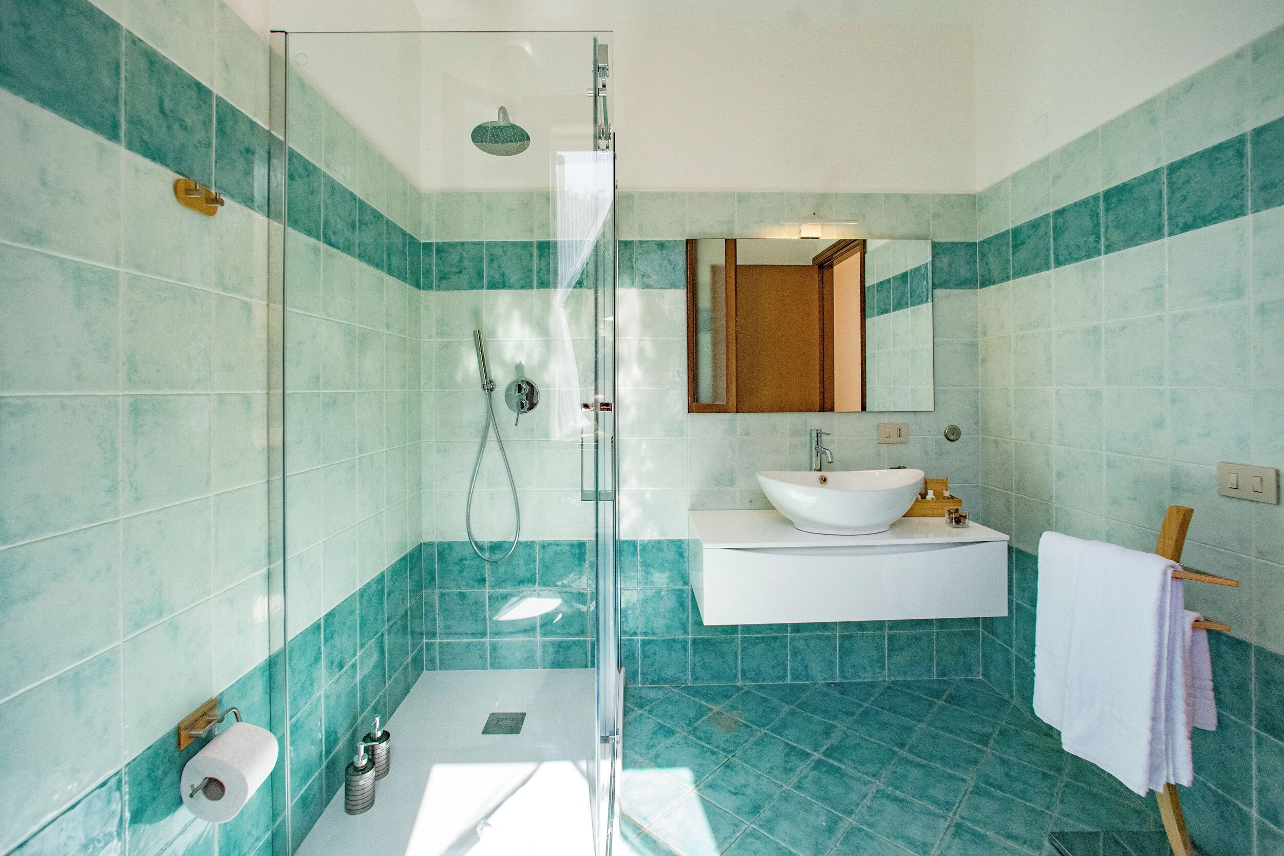 A modern bathroom with a glass-enclosed shower, a white sink, and a mirror above the sink.