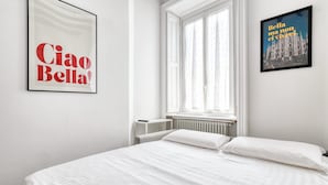 A bedroom with a bed, a window, and two framed pictures on the wall. - Lovely flat near Naviglio Grande (Milan)