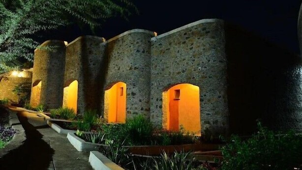 A stone building with multiple arched openings, illuminated by warm lighting. - Mara Sun Lodge (Maasai Mara)