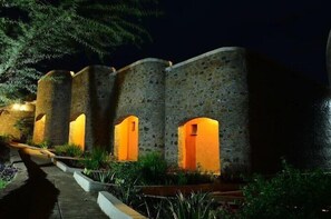 A stone building with multiple arched openings, illuminated by warm lighting.