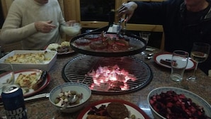 A dining table with various dishes, a grill, and a can of beer. - Tucked Away Log Cabin on Welsh Hill Farm (Sennybridge)