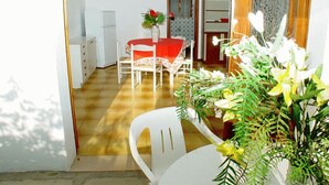 A room with a dining table, chairs, a refrigerator, and a window with curtains. - Comfortable three room apartment in Lignano with parking (Lignano Sabbiadoro)