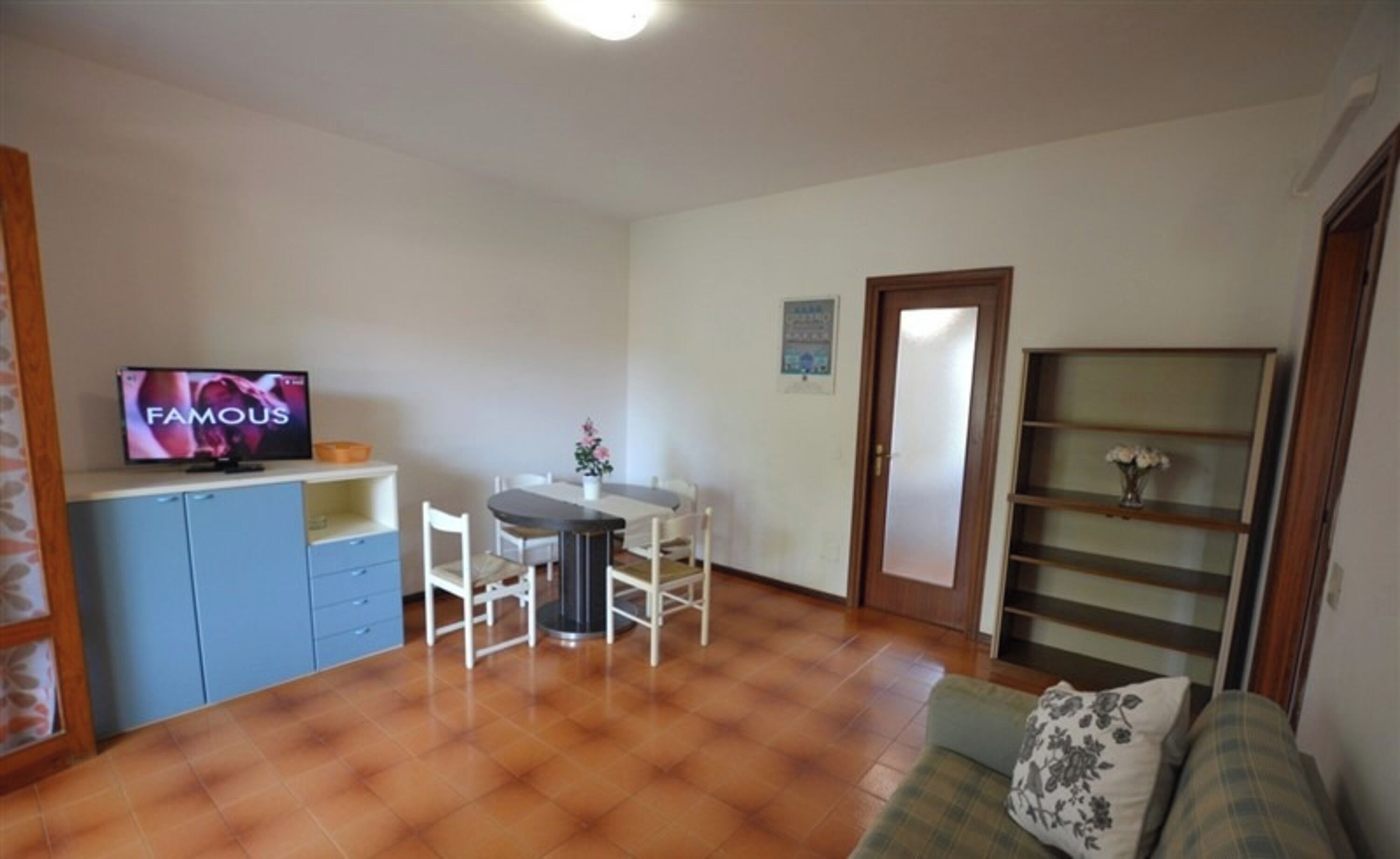 Un espacio habitable compacto con comedor, televisor, sofá y estantería.