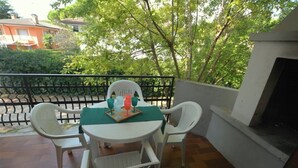 A balcony with a table set for two, surrounded by white chairs. - Comfortable three room apartment in Lignano with parking (Lignano Sabbiadoro)
