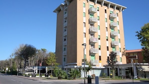 Un hotel de diverses plantes amb balcons, un cel serè i un carrer amb bicicletes aparcades.