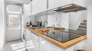 A modern kitchen with white cabinetry, a wooden countertop, a built-in stove, and a window providing natural light. - Oceanic Hideaway 18: 1  BR, 1  BA Apartment in Sorrento, Sleeps 4 (Sorrento)