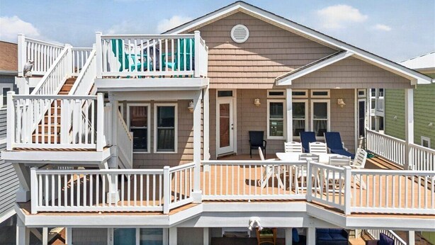 A two-story house with a balcony, a staircase, and a deck. - The Penalty Box- 5 bed, 5+ bath with putting green, corn hole, & hammock swing. (Ocean Isle Beach)