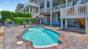 A two-story house with a swimming pool, outdoor seating, and a covered patio area.
