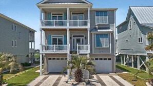 A two-story residential building with a balcony on the second floor, a covered front porch, and a small palm tree in the front yard.