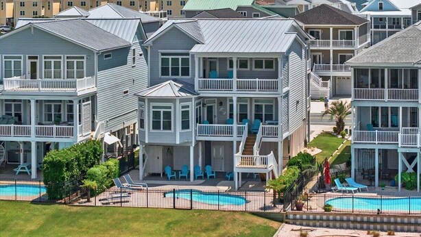 A beachfront hotel with multiple-story buildings, balconies, and a swimming pool.