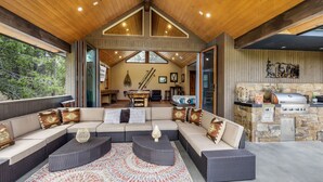 A spacious living area with a large sectional sofa, a stone fireplace, and a grill station.