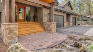 A wooden house with a stone entrance, a number '15' on the door, and a garage.