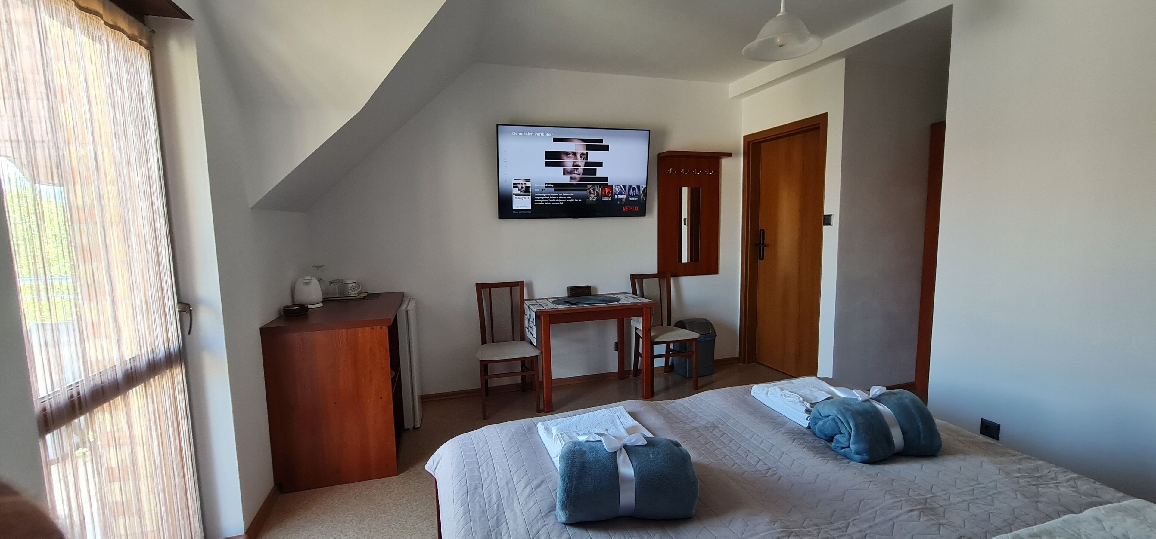 Een slaapkamer met een bed, een bureau, een stoel, een televisie en een kledingkast.