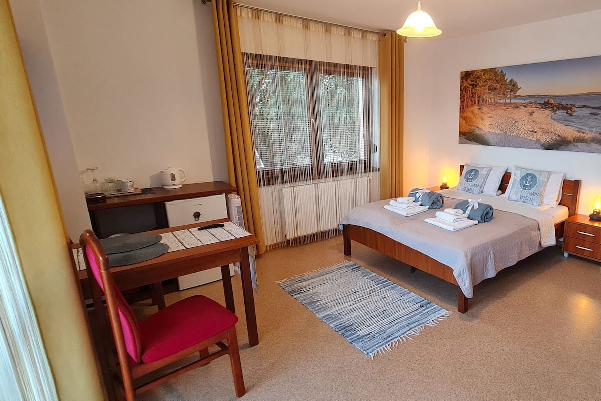 Ein Schlafzimmer mit einem Bett, Nachttischen, einem Schreibtisch und einem Sessel.