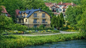 En bygning ved en flod med en stenfassade, flere balkoner og en have foran.