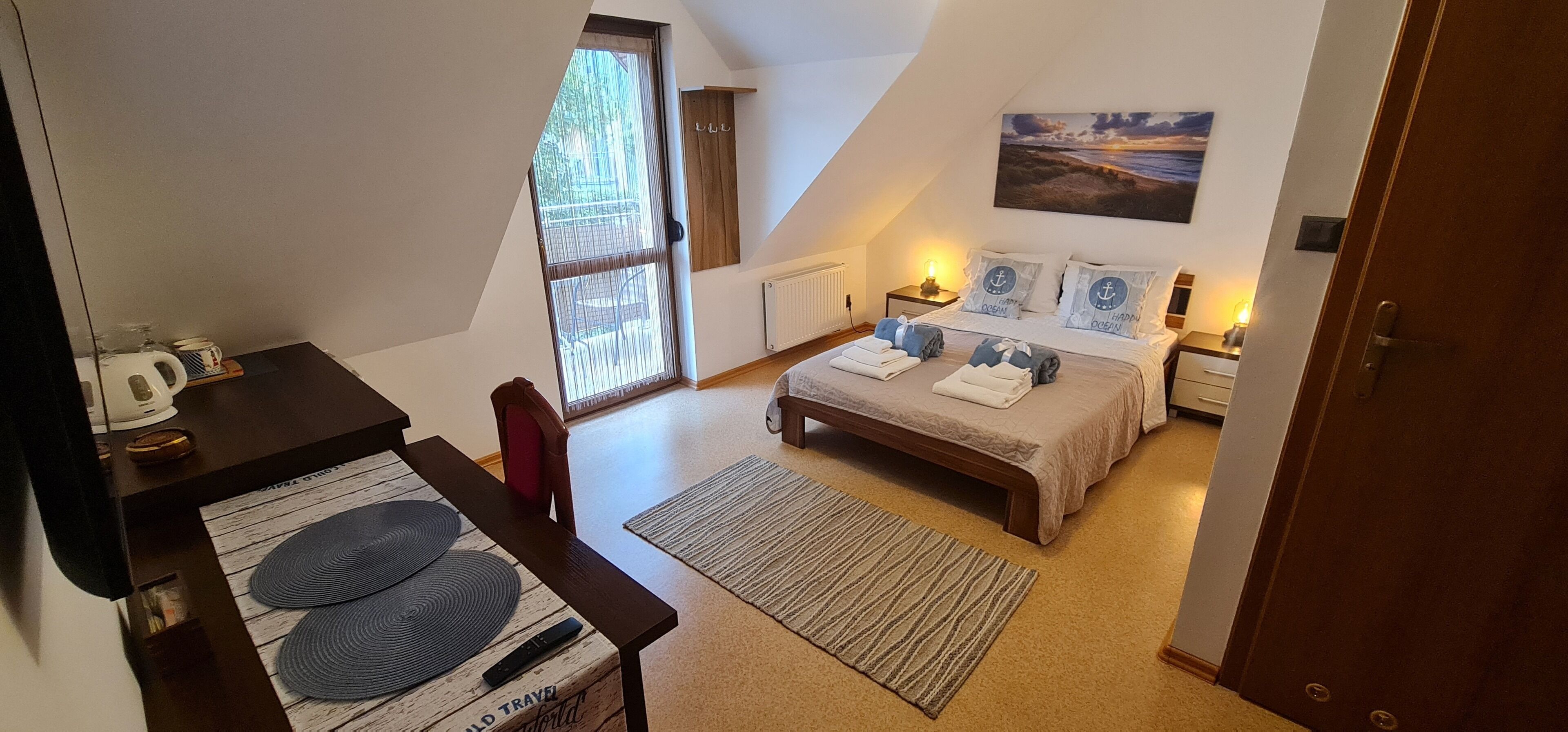 Ein Schlafzimmer mit Bett, Nachttischen, einem Schreibtisch und einem Stuhl. Ein Fenster bietet Blick ins Freie.