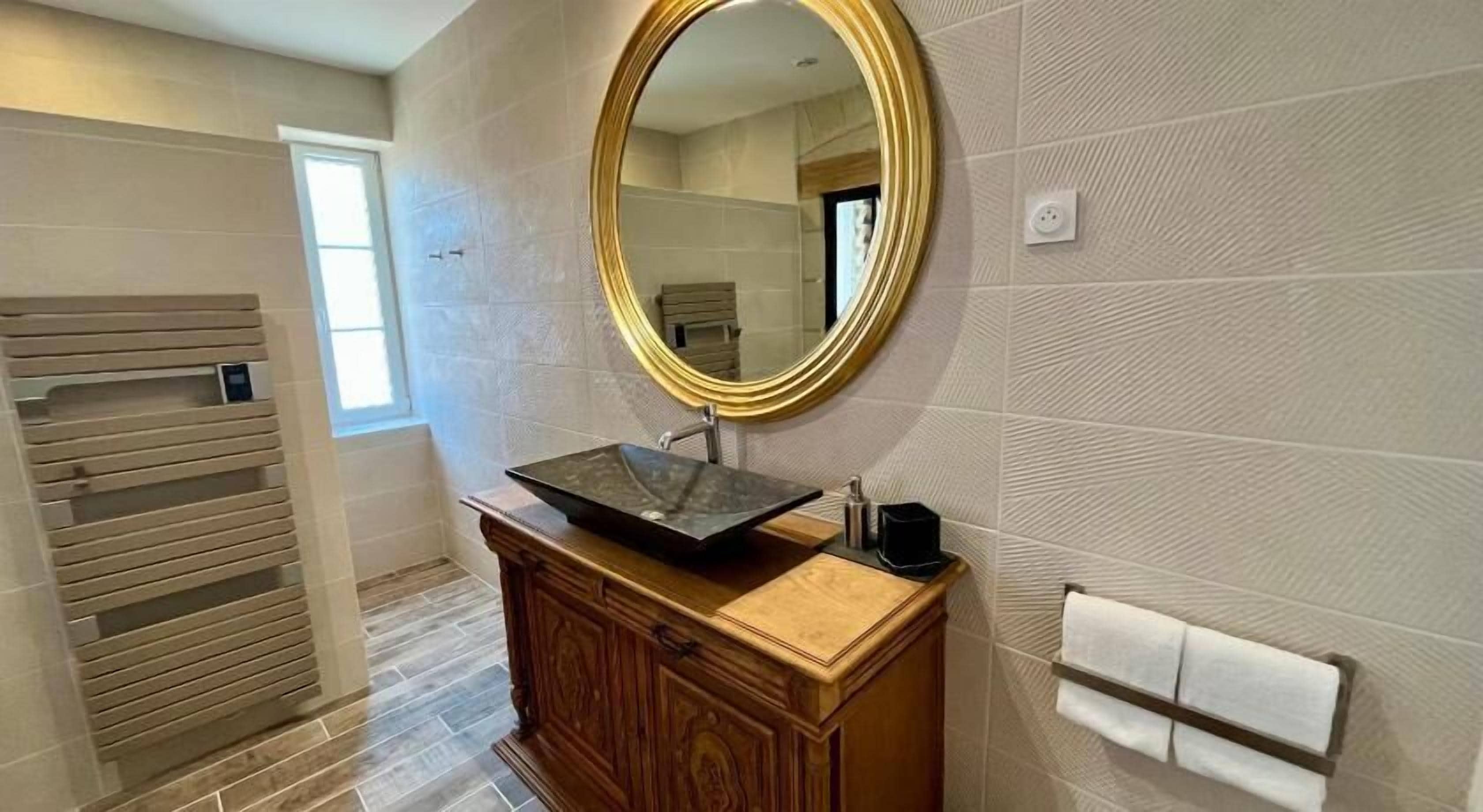 A bathroom with a wooden vanity, a large mirror, and a towel rack.