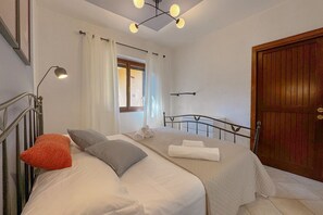 Un dormitorio con dos camas, una puerta de madera, una ventana con cortinas y un accesorio de iluminación en el techo.