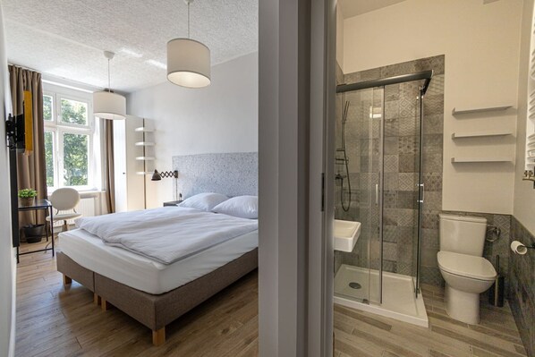 Une chambre d’hôtel moderne dotée d’un grand lit, d’une douche en verre et de toilettes séparées.