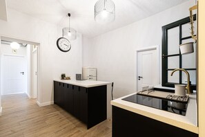 Une cuisine moderne dotée d’un îlot central, de meubles de couleur noire, d’une cuisinière encastrée et d’une fenêtre à cadre noir.