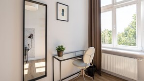 A modern room with a large mirror, a desk, a chair, a potted plant, and a window with curtains. - Verde 2 - Spokojny Pok j w Dolnym Mie cie (Gdansk)