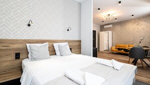 Une chambre d’hôtel moderne dotée d’un grand lit, d’une tête de lit en bois, d’un mur à motifs et d’un coin salon avec un canapé et une table.