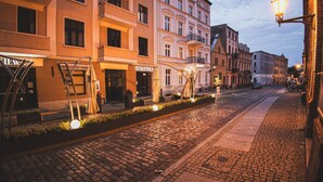 Une rue pavée bordée de bâtiments historiques, dont certains arborent des enseignes bien visibles.