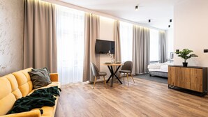 Un salon moderne avec un canapé jaune, une table à manger avec des chaises, un téléviseur à écran plat fixé au mur et un meuble en bois.