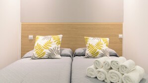 A double bed with two pillows, a wooden headboard, and a stack of white towels. - Madrid Central Stay Plaza Mayor (Madrid)