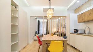 A modern kitchen with a wooden dining table, two chairs, a hanging light fixture, and a microwave on the counter. - Madrid Central Stay Plaza Mayor (Madrid)