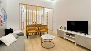 A modern living room with a sofa, two armchairs, a coffee table, a TV, and a bookshelf. - Madrid Central Stay Plaza Mayor (Madrid)