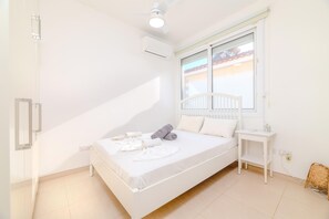 Une chambre à coucher comprenant un lit, une table de chevet, une fenêtre avec vue et un appareil de climatisation.