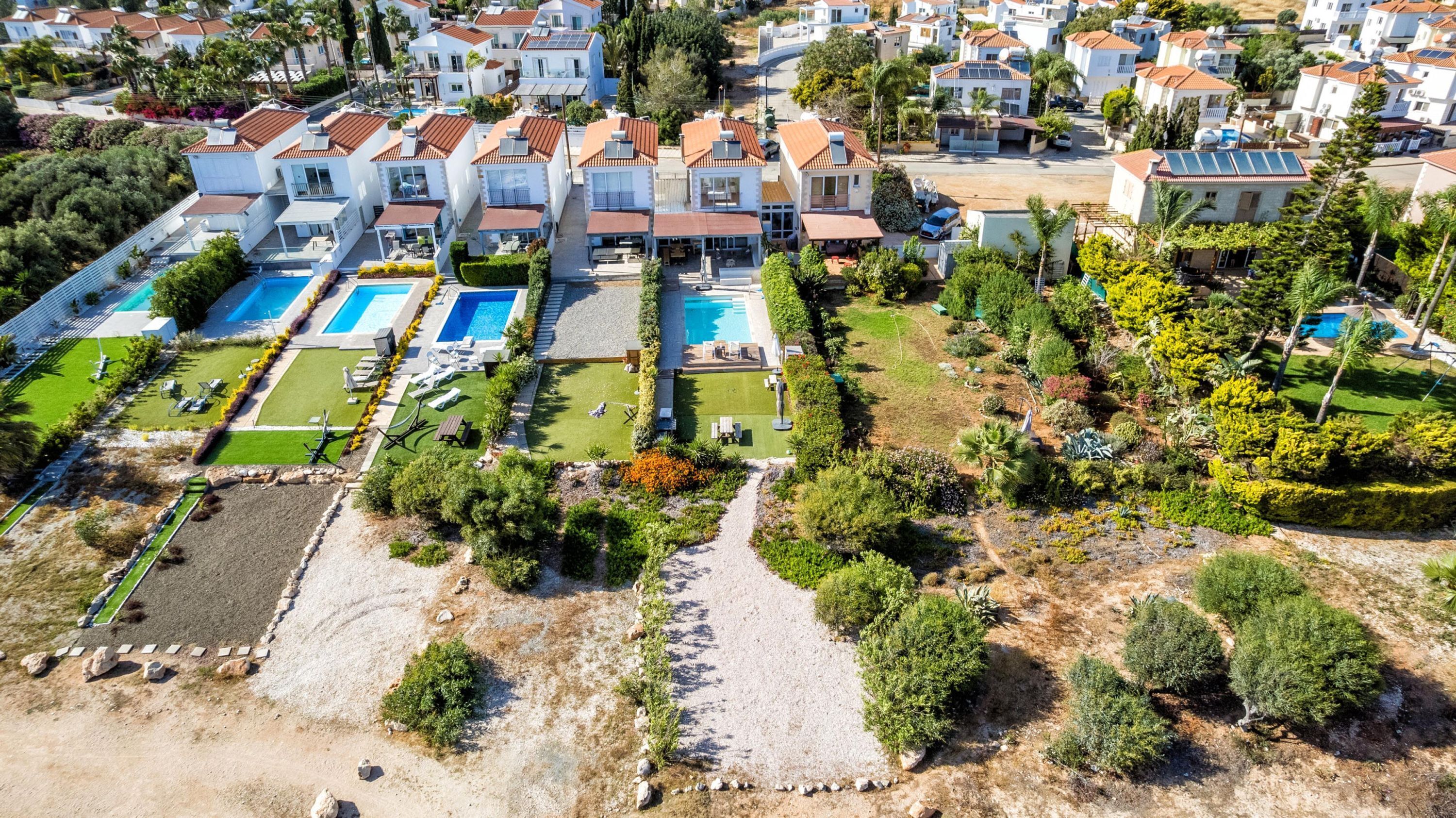 Un quartier résidentiel comprenant plusieurs maisons, une piscine et des jardins aménagés.